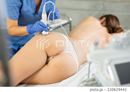 Professional cosmetician performing hardware body treatment, electric massage and moisturizing bottom layer of skin for young woman in clinic of esthetic cosmetology Professional cosmetician performing hardware body treatment, electric massage and moisturizing bottom layer of skin for young woman in clinic of esthetic cosmetology 120629442