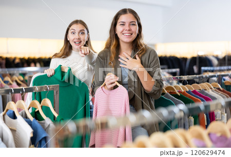 Enthusiastic young girls pointing each other to new clothes in mall Enthusiastic young girls pointing each other to new clothes in mall 120629474