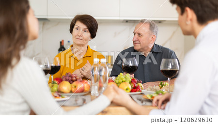 Elderly parents enjoying family dinner with young adult children 120629610