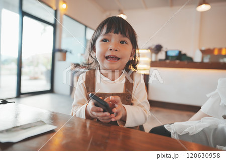 toddler girl using smartphone at cafe toddler girl using smartphone at cafe 120630958