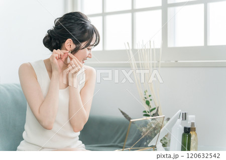 家でアクセサリー・ピアスを選ぶ女性 120632542