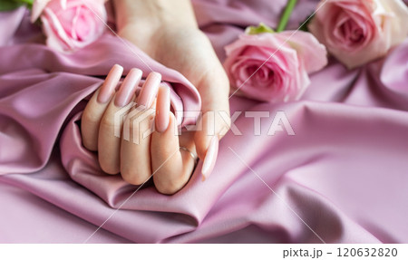 Woman showing pink manicure holding pink rose on pink silk background Woman showing pink manicure holding pink rose on pink silk background 120632820
