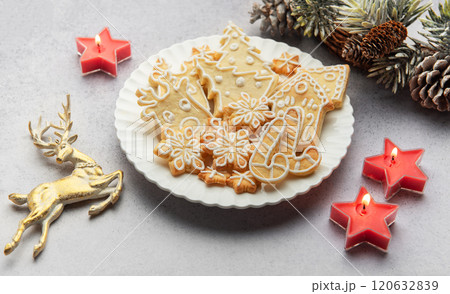 Christmas gingerbread cookies decorated with icing on white plate with festive decorations Christmas gingerbread cookies decorated with icing on white plate with festive decorations 120632839