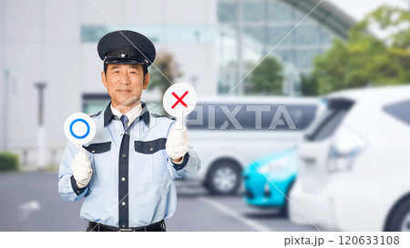 駐車場でバツ印を見せる男性警備員 120633108