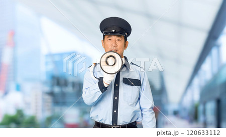 都市の駅前で拡声器を使って誘導する男性警備員 120633112