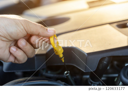 Car owner pulls out the dipstick to check engine oil levels, highlighting the importance of regular oil maintenance for optimal engine performance and vehicle longevity Car owner pulls out the dipstick to check engine oil levels, highlighting the importance of regular oil maintenance for optimal engine performance and vehicle longevity 120633177