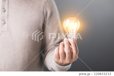 A man holds a clear light bulb, symbolizing the spark of new ideas and creativity. This image represents innovation, inspiration, and the power of fresh thinking 120633213