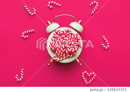 Christmas background with candy canes on alarm clock on pink background 120633351