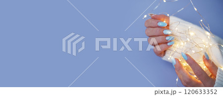 Cozy nails with winter manicure with snowflakes and lights on purple background 120633352