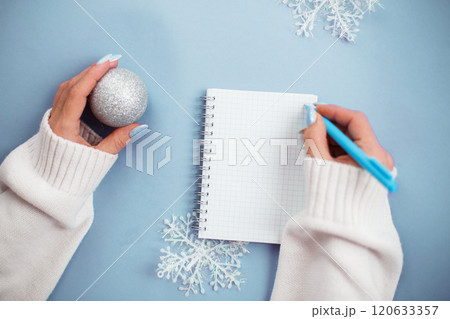Woman hand with winter nails holding pen on notebook and writing wish list 120633357