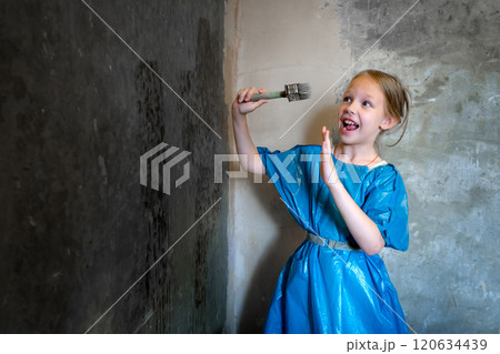 9-year-old girl in blue workwear priming a cement wall. Renovation concept. 9-year-old girl in blue workwear priming a cement wall. Renovation concept. 120634439