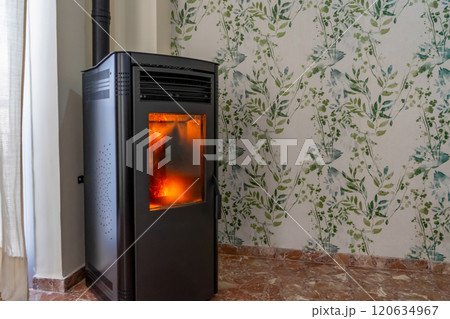 Horizontal image of a fully operational pellet stove, the stove needs cleaning as the glass and interior are very dirty with ash. Renewable energy concept. Horizontal image of a fully operational pellet stove, the stove needs cleaning as the glass and interior are very dirty with ash. Renewable energy concept. 120634967