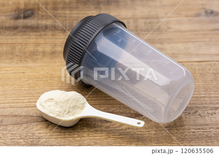 木目のテーブルに置かれた計量スプーンのプロテインとシェイカー 120635506