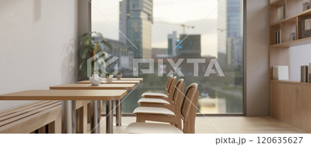 A minimalist Scandinavian coffee shop seating area showcases a row of wooden tables and chairs. A minimalist Scandinavian coffee shop seating area showcases a row of wooden tables and chairs. 120635627