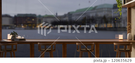 A long wooden table with stools positioned against a large window in a cozy minimalist coffee shop. 120635629