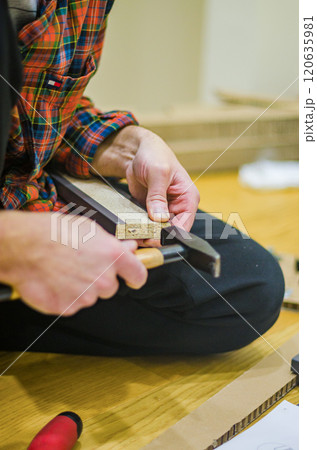 male holding hummer Assembly Instruction on Wooden Floor for DIY Furniture Setup. High quality photo 120635981