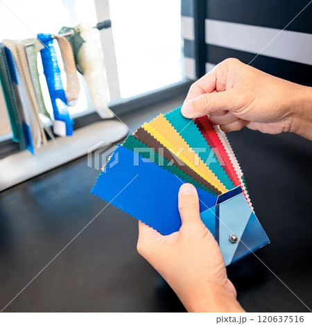 Designer hand choosing fabric sample pieces from color collection 120637516