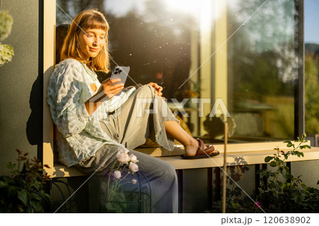 Relaxing with Phone in Sunlit Garden 120638902