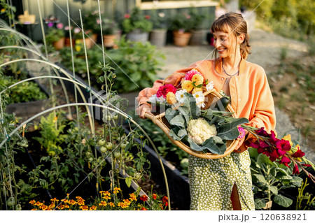 Smiling Woman with Harvest Basket in Garden 120638921