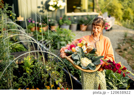 Smiling Woman with Harvest Basket in Garden 120638922