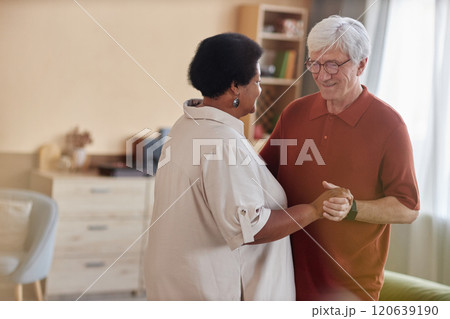 Minimal portrait of senior couple dancing together in hazy cozy room and enjoying music with smiles copy space Minimal portrait of senior couple dancing together in hazy cozy room and enjoying music with smiles copy space 120639190