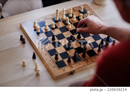 Top view close up of unrecognizable man playing chess with focus on hand moving pawn piece copy space Top view close up of unrecognizable man playing chess with focus on hand moving pawn piece copy space 120639214