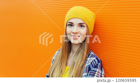 Portrait of modern young teenage blonde girl smiles in yellow hat on orange background Portrait of modern young teenage blonde girl smiles in yellow hat on orange background 120639395