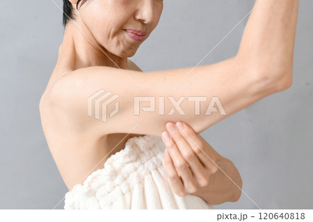 二の腕を掴み気にする中年のアジア人女性 二の腕を掴み気にする中年のアジア人女性 120640818