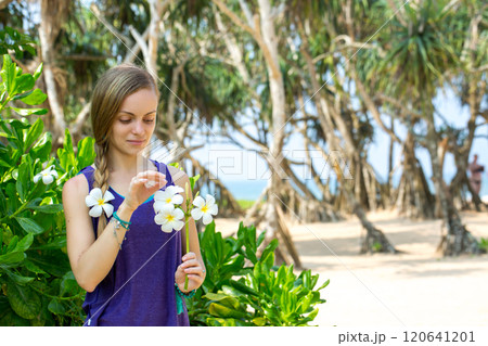Woman with braided hair holding a flower of Plumeria in her hand Woman with braided hair holding a flower of Plumeria in her hand 120641201