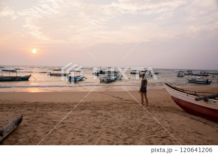 A woman stands on the beach looking out at the ocean A woman stands on the beach looking out at the ocean 120641206
