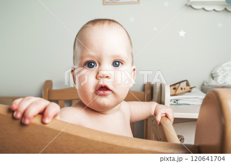 Curious Baby Standing in a Wooden Crib 120641704
