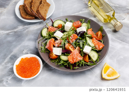 Salad with salmon, white cheese and vegetables on the plate with ingredients. 120641931