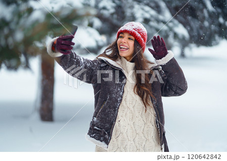 Cute woman enjoying the snowy landscape in the park. Concept of nature, technology. 120642842
