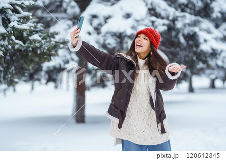 Cute woman enjoying the snowy landscape in the park. Concept of nature, technology. Cute woman enjoying the snowy landscape in the park. Concept of nature, technology. 120642845