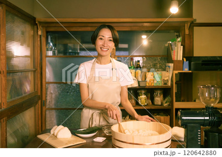 古民家の台所でおにぎりを結ぶミドルエイジの女性 120642880