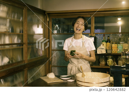 古民家の台所でおにぎりを結ぶミドルエイジの女性 120642882