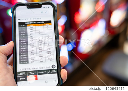スマホでパチンコ、パチスロのデータを確認する男性 120643413