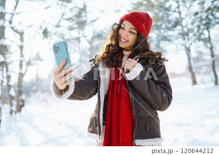 Smiling young woman taking selfie in winter forest. Winter holiday. 120644212