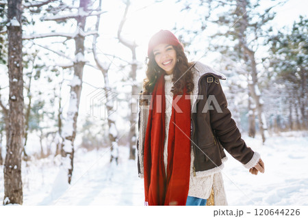 Beautiful Young Smiling woman in her Winter Warm Clothing walking in the snow forest. 120644226