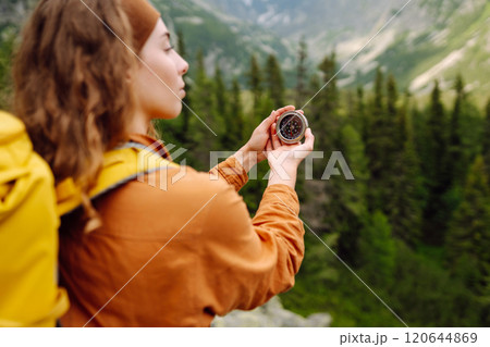 Wanderlust concept. Stylish woman holding a compass in her hand while traveling in the mountains. Wanderlust concept. Stylish woman holding a compass in her hand while traveling in the mountains. 120644869