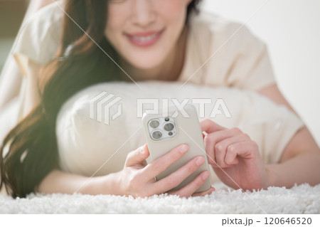 寝起きのベッドやリビングでスマホを操作する若い女性　顔無し 120646520