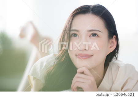 寝起きのベッドやリビングで見上げる考える悩む笑顔の若い女性女性のクローズアップ 120646521