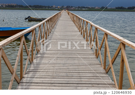 Wooden walkway leads to the Caspian Sea in Iran with boats and cityscape visible 120646930