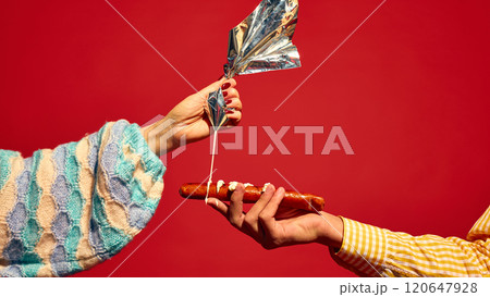 Female hand putting mayonnaise sauce on grilled sausage, Bratwurst against bright red background. Delicious taste of street food 120647928