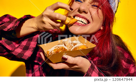 Cropped close-up image of redhead young woman in checkered shirt, emotionally eating sweet donuts with powdered sugar Cropped close-up image of redhead young woman in checkered shirt, emotionally eating sweet donuts with powdered sugar 120647944