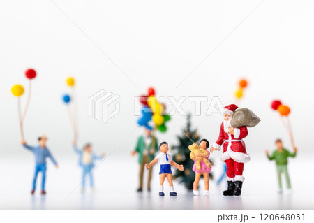Miniature Santa Claus holding a gift surrounded by children and colorful balloons 120648031