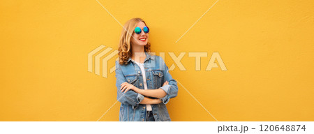 Stylish beautiful happy young woman with crossed arms in denim jacket posing on yellow background Stylish beautiful happy young woman with crossed arms in denim jacket posing on yellow background 120648874