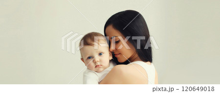 Happy young mother holding cute baby together in white room at home Happy young mother holding cute baby together in white room at home 120649018