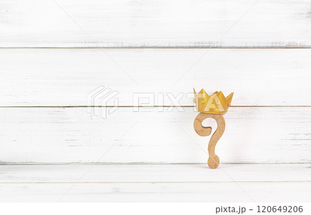 Royal Inquiry: Wooden Question Mark Crowned with Gold Against a Rustic White Background 120649206