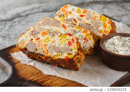 Spicy terrine pie with chicken liver, carrots, peppers, herbs and eggs close-up on a wooden board. Horizontal Spicy terrine pie with chicken liver, carrots, peppers, herbs and eggs close-up on a wooden board. Horizontal 120650235
